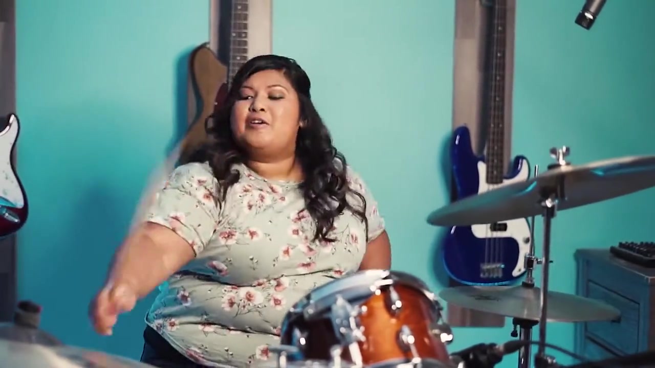 Sharon Ransom playing drums in her teal studio